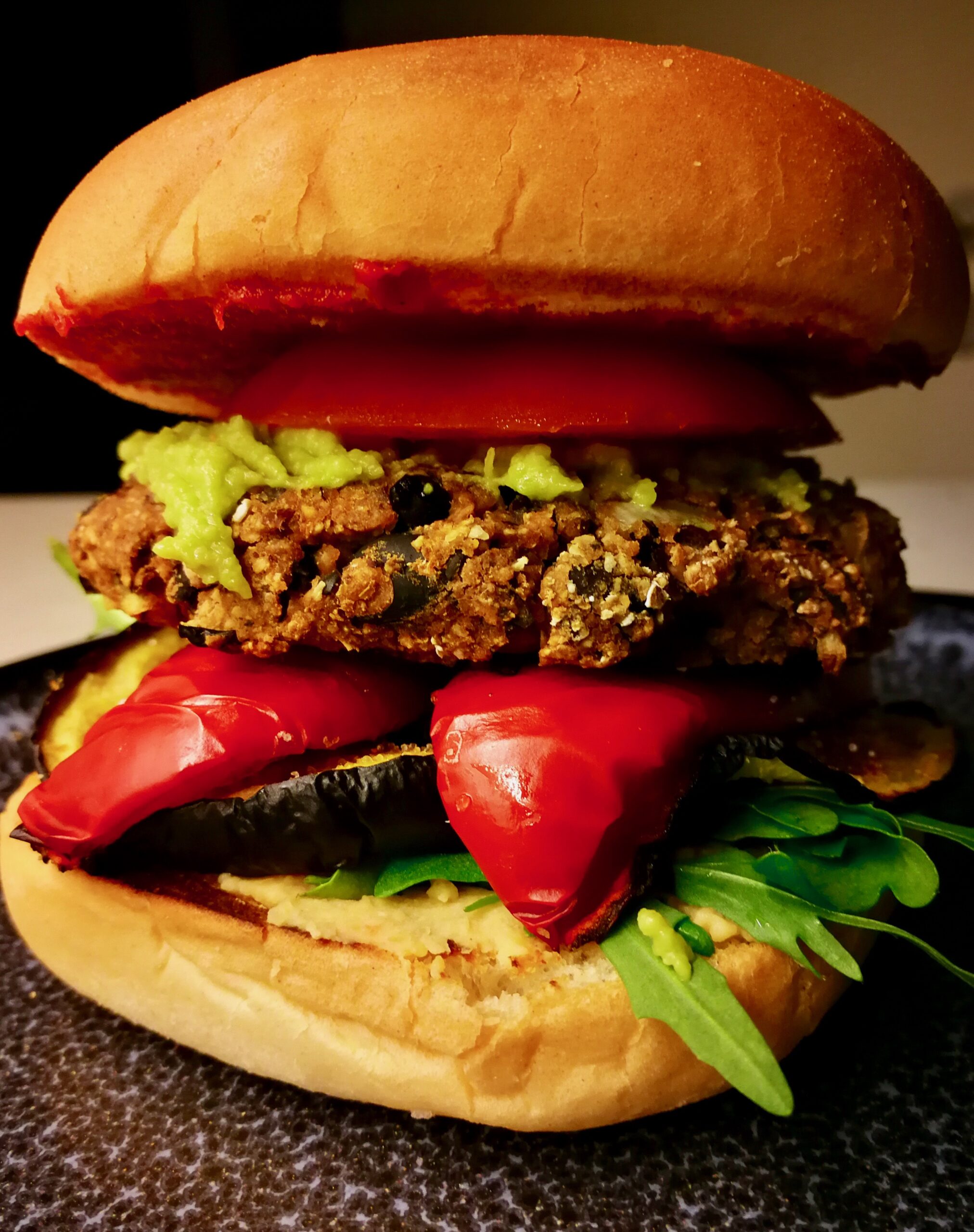 großer Burger mit schwarzen Bohnen Patty, Grillgemüse, Rucola und Guacamole